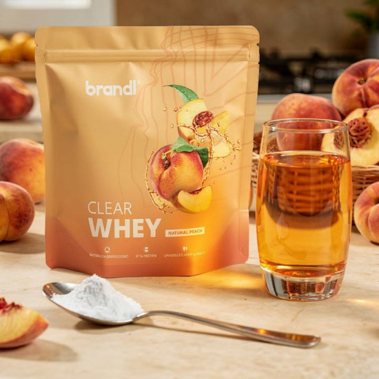Brandl clear whey in natürlichem Pfirsichgeschmack in einem goldorangefarbenen Beutel mit Pfirsichillustrationen