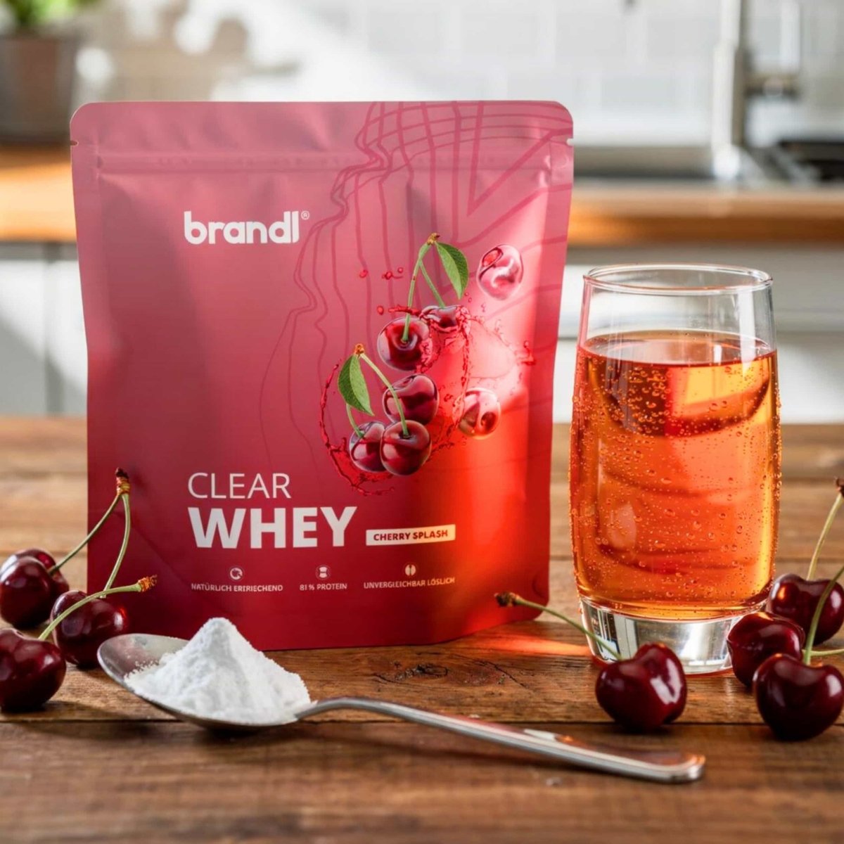 Ein leuchtend rotes pouch von brandl clear whey cherry splash proteinpulver mit glänzendem finish und kirschgrafiken
