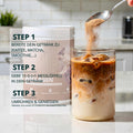 Ein weißer zylinderförmiger behälter brandl kollagen pulver mit matter oberfläche und lila branding hinter einem glas eiskaffee wird gerührt