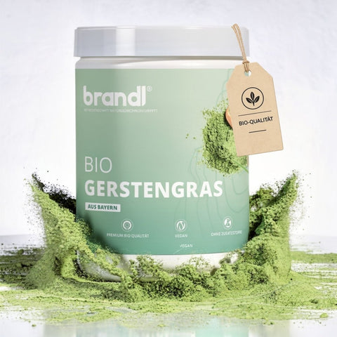 Ein mattgrüner zylindrischer behälter von brandl bio gerstengras pulver mit weißem deckel und beige etikett bio qualität