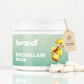 Ein weißer zylinderförmiger behälter mit bromelain kapseln von brandi und mintgrünem etikett mit ananasmotiv