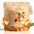Brandi clear whey natürliches pfirsicharoma in glänzendem beigem beutel mit pfirsichmotiven und goldenen flüssigkeitsspritzern