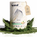 Ein weißer zylinderbehälter der marke brandl mit pure greens superfoods pulver und grünem pulver am boden