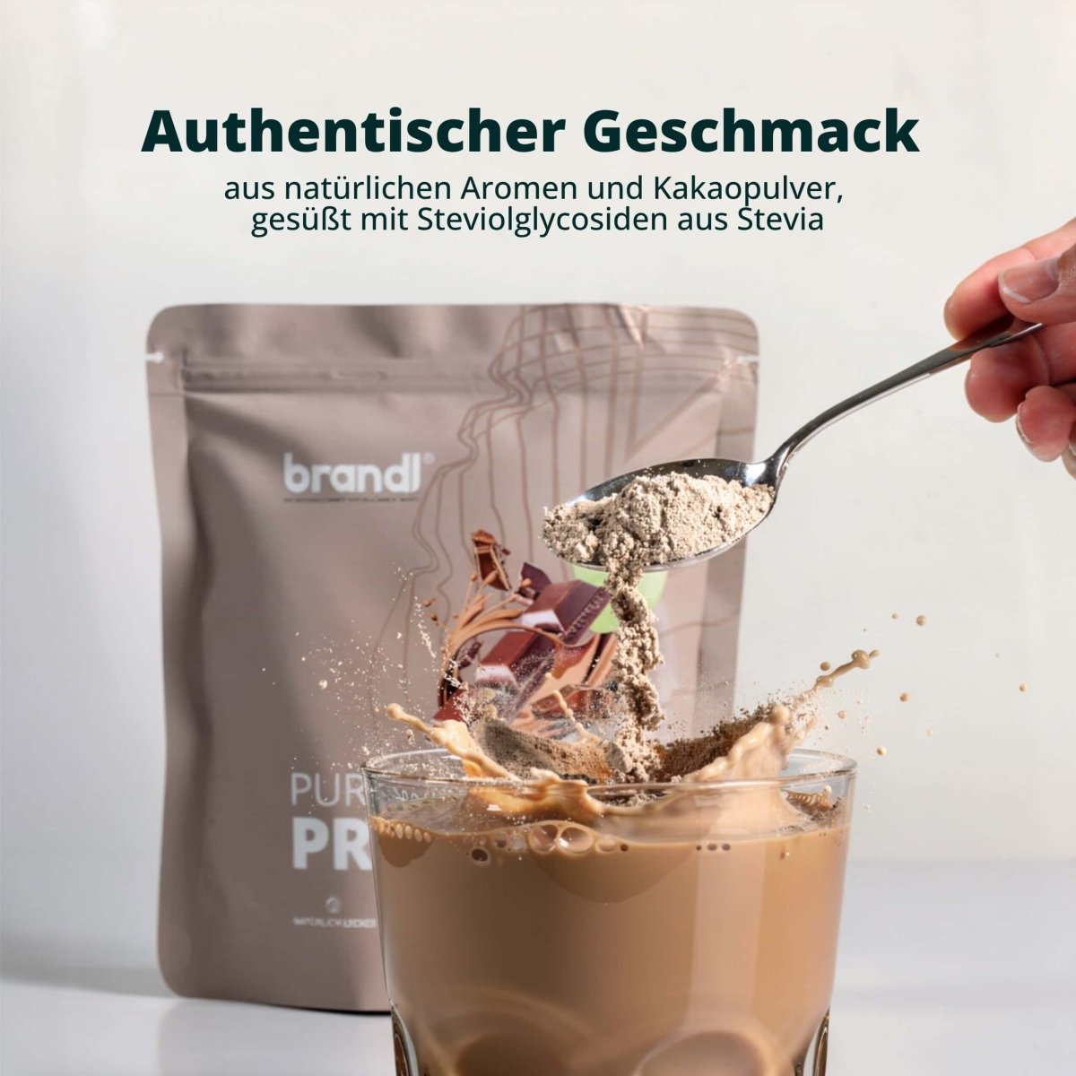 Ein braunes Pulver wird von einem löffel in ein glas schokoladengetränk mit brandl veganem pure protein 20 gegeben