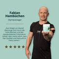 Eine helfende hand hält einen weißdeckeligen, hellgrünen zylinderförmigen behälter der marke brandl shilajit pulver in kapseln